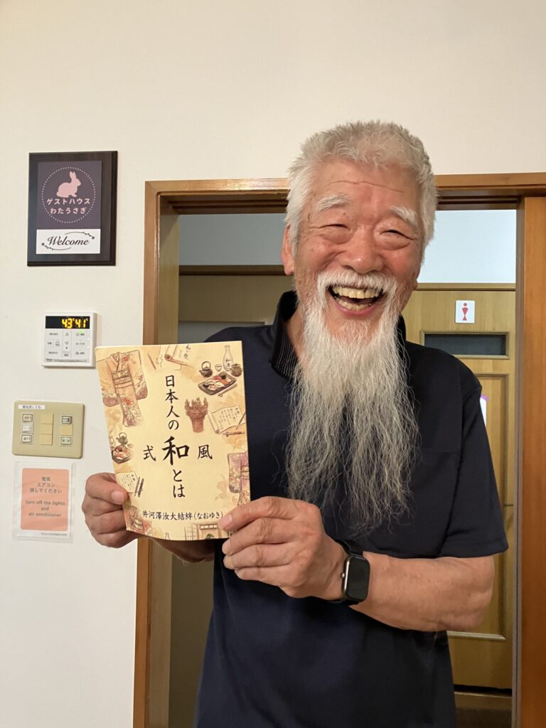 自費出版本『日本人の「和」とは』を手に微笑む著者・井河澤汝大結絆(なおゆき)さん